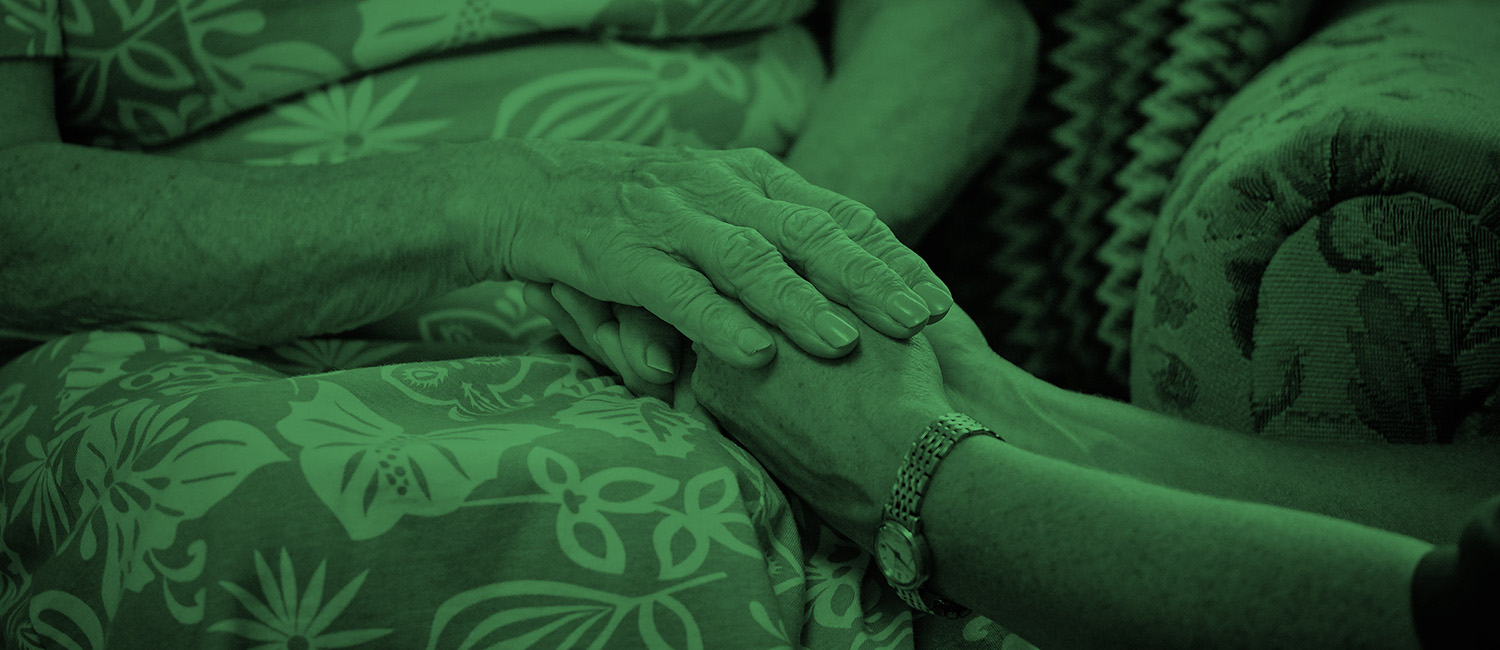 Patient holding hands with carer green branded